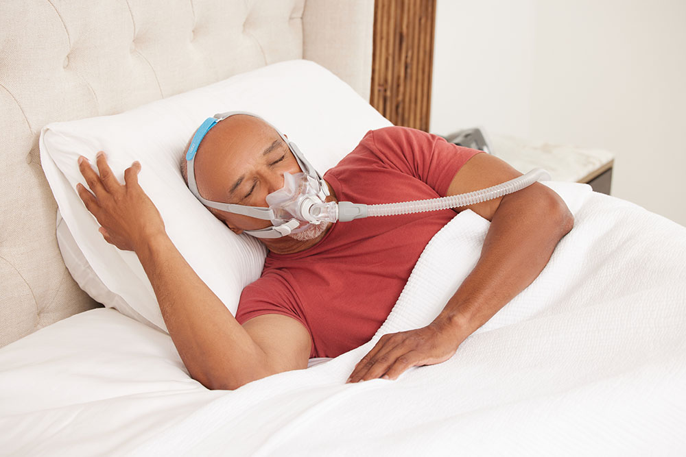 Sleep Apnea Black Male Older Patient Smiling Wearing ResMed AirFitF30PAPmask ResMed AirSense10PAP Sleeping lifestyle